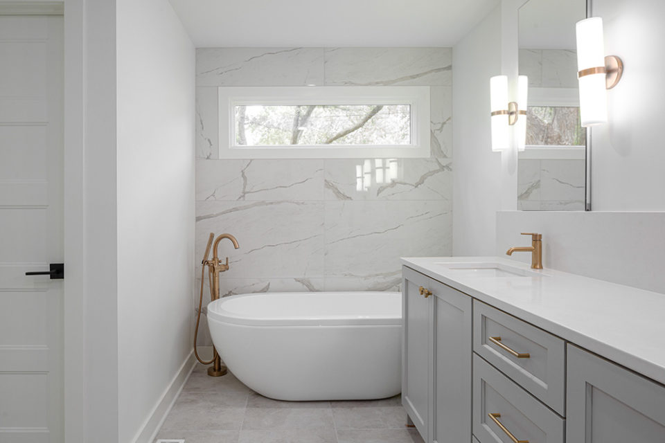 bathroom with white soaker tub and grey marble wall